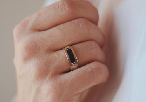 A closeup shot of a male in a formal outfit wearing a golden ring