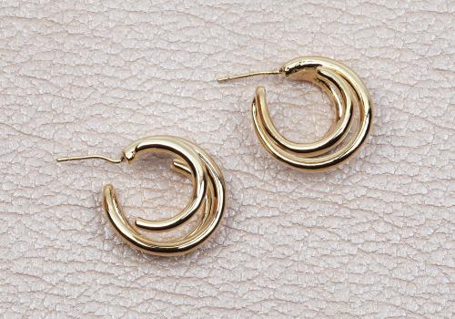 modern-gold-womens-earrings-beige-leather-background